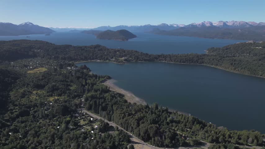 4K drone aerial view of Lake Nahuel Huapi from Cerro Campanario in Bariloche, Río Negro, Argentina. Deep blue waters stretch across the Patagonian landscape surrounded by forested mountains.