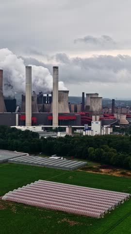 Lignite-fired power station with smoking chimneys and cooling towers on a cloudy day in Germany