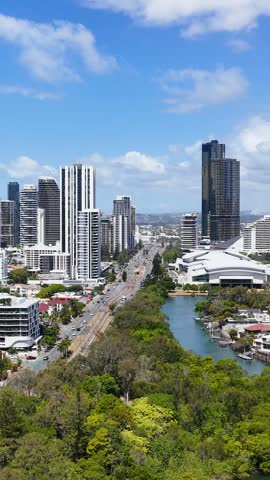 High angle aerial shot of city skyscrapers, lush parklands, and waterways in Gold Coast, Australia.