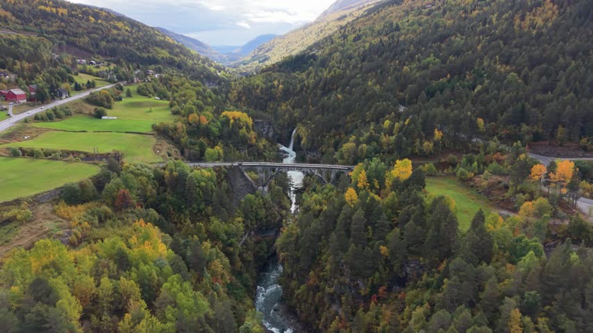 Aerial view of a historic railway bridge, rushing river and waterfall in Rauma Valley, Norway.