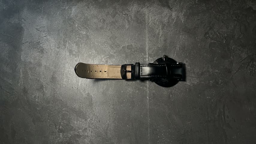 classic leather watch strap lying on dark table