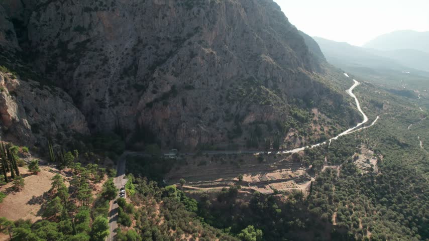 Aerial view of the winding road and ancient terraces nestled within the rugged mountainous landscape of the archaeological site in Delphi, Greece.