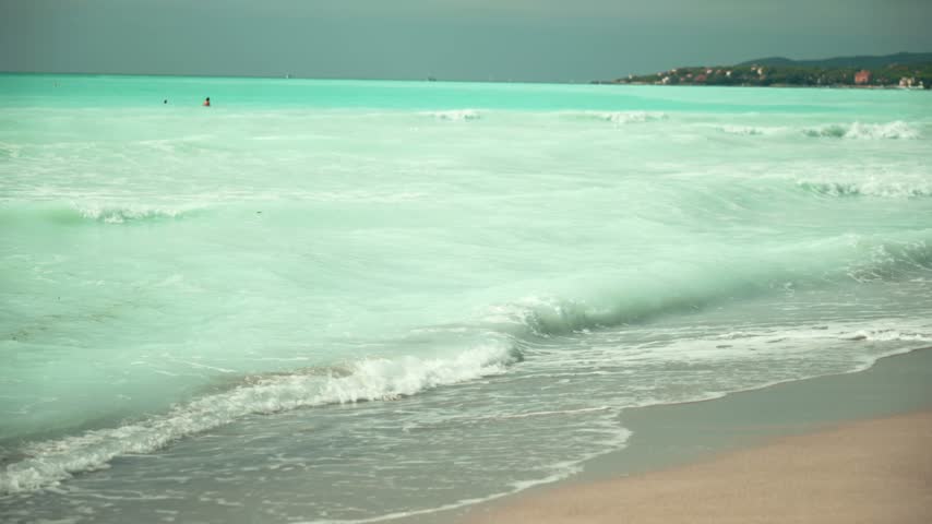 Spiagge Bianche, Italy. Turquoise sea waves washing up on a sandy beach shore in rosignano solvay, italy, with people swimming in the beautiful blue water on a summer day in tuscany