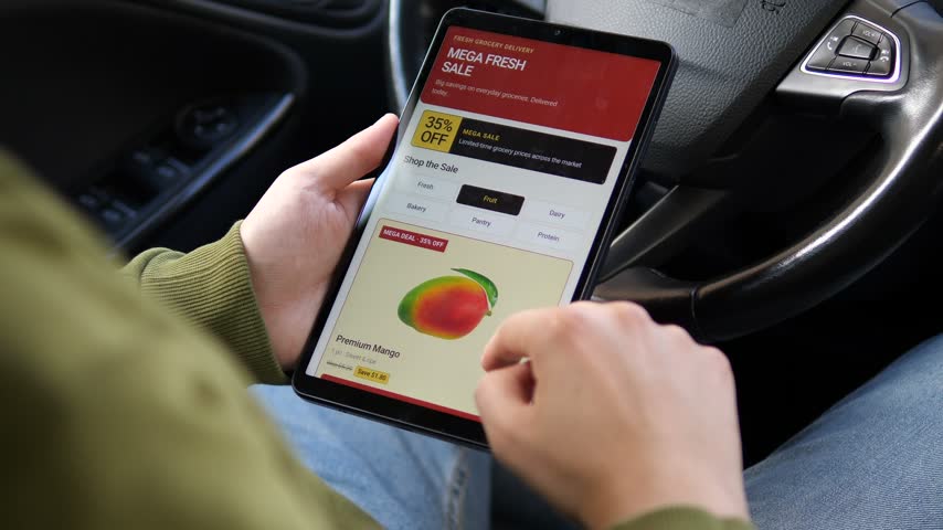Person shops discounted fruit on a tablet, comparing mango and kiwi prices as digital grocery retail highlights convenience, promotions and price-conscious consumer behavior.