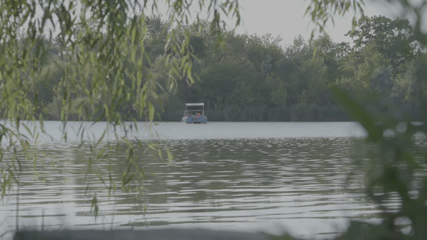 Small Recreational Boat Cruising Across Peaceful Green Lake