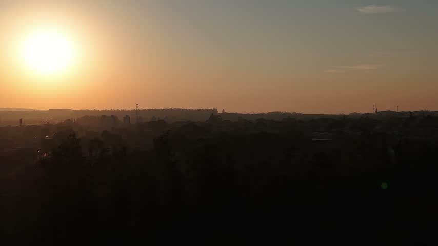 Aerial view of the golden sunset casting silhouettes over the trees and buildings in Araras, Sao Paulo, Brazil.