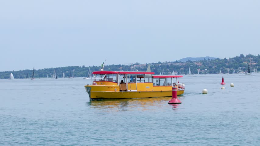 A yellow passenger shuttle boat cruises across calm waters on Lake Geneva in Switzerland.