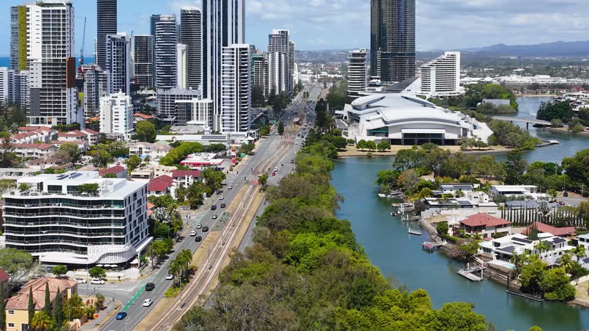 Aerial view of modern skyscrapers, roadways, and waterways in Gold Coast, Australia under bright daylight.