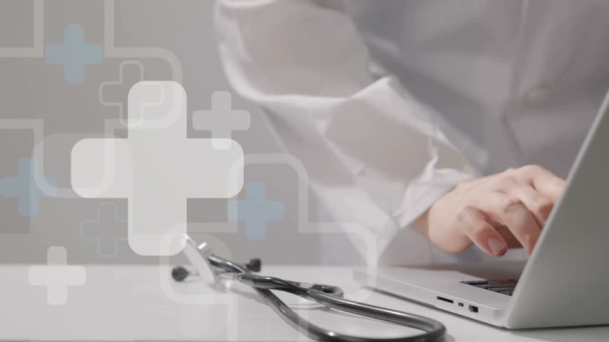 Medical professional engaged in typing on laptop with stethoscope resting on table. Modern health care setting showcases technology in use. Focus on efficient communication.