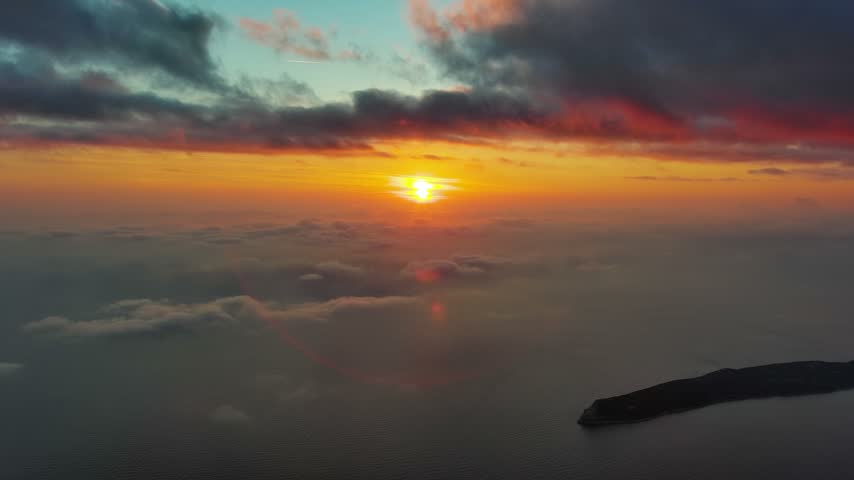 Aerial view of a vibrant sunset over the Adriatic Sea with the rugged coastline of Montenegro.