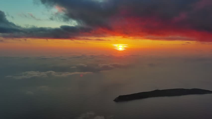 Aerial view of a vibrant sunset over the Adriatic Sea with a small island visible below in Montenegro.
