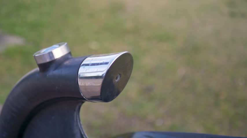 Slow motion close-up of a finger pressing a push-button for a water fountain bubbler fixture that dispenses an arching stream of drinking water for hydration at a local sports park field in Australia