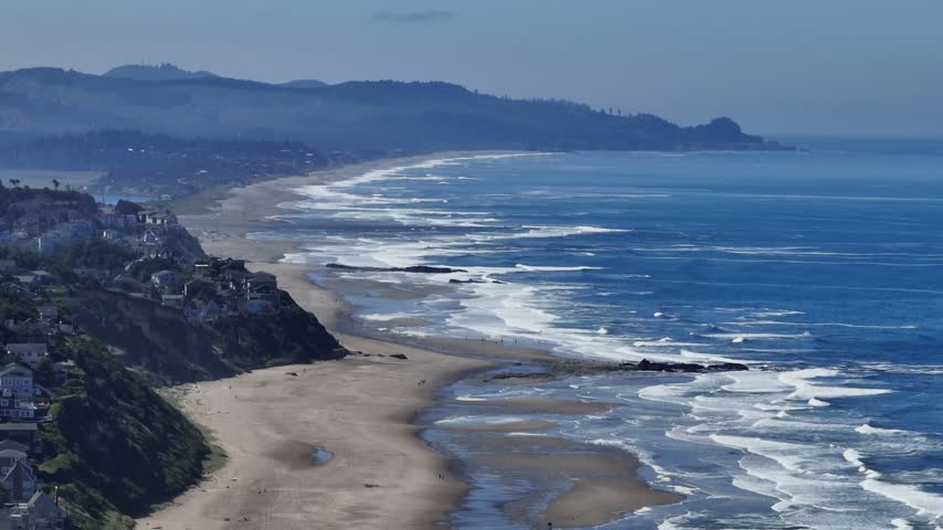 Oregon coastline features sweeping sandy shores and rolling Pacific waves viewed from above with coastal homes perched along high cliffs