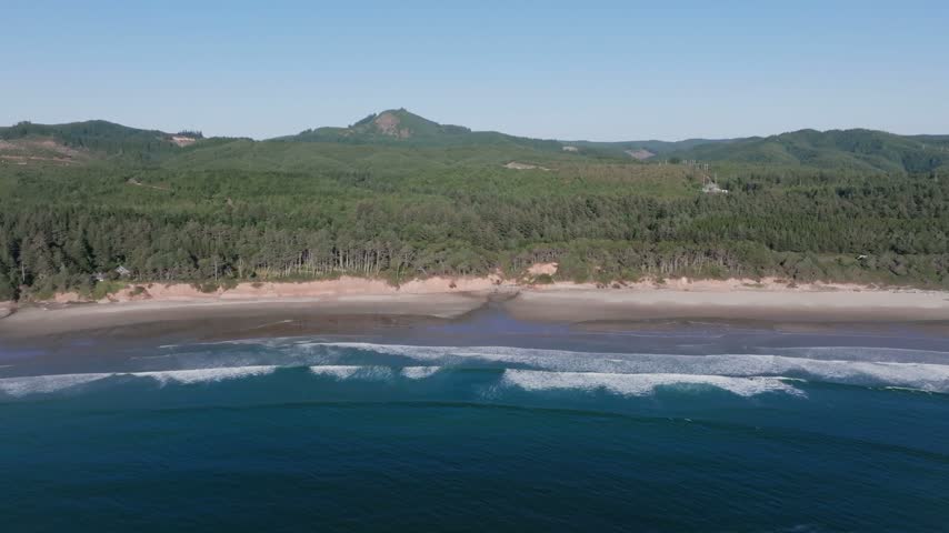 Oregon scenic coastal landscape features rugged cliffs dense pine forests and sandy shores meeting the blue ocean waters in an expansive high angle perspective
