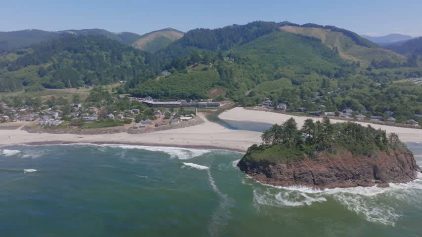 Oregon coastal landscape featuring towering sea stacks winding river mouth and dense pine forests captured from an aerial perspective