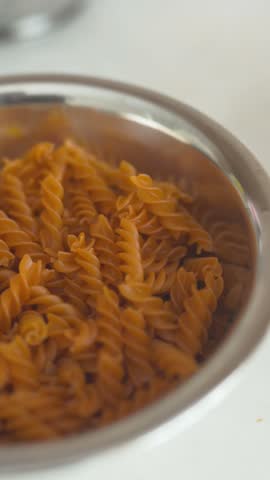 close-up view of freshly cooked pasta coated in a rich, vibrant red tomato sauce. Garnished with fresh green basil leaves, finely grated Parmesan cheese, and a sprinkle of cracked black pepper, all presented on an elegant ceramic plate. Warm natural daylight highlights the glossy texture of the sauce and the appetizing details of the dish. Ideal for Italian restaurant menus, gourmet pasta