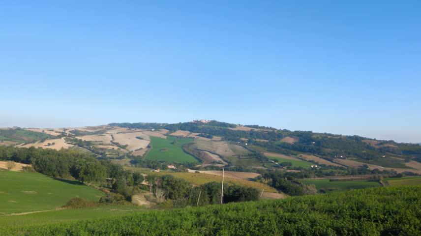 Panoramic view of Italian hills with geometric cultivated fields and a clear blue sky