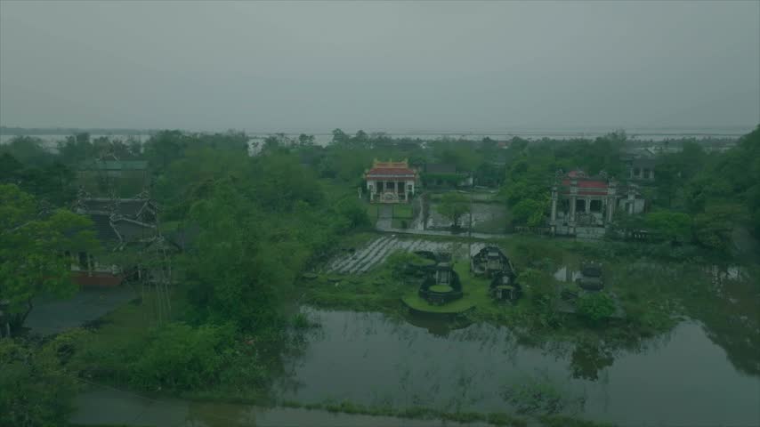 Overall forward tracking of a rural village with trees, houses and a river in the background