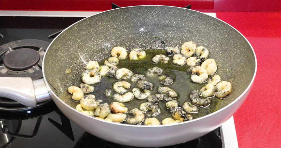 Hot Cooked Spaghetti Added to Shrimp and Squid Ink Sauce in Pan. Steaming freshly cooked spaghetti is added to a pan containing shrimp and squid ink sauce during the preparation of black seafood pasta.