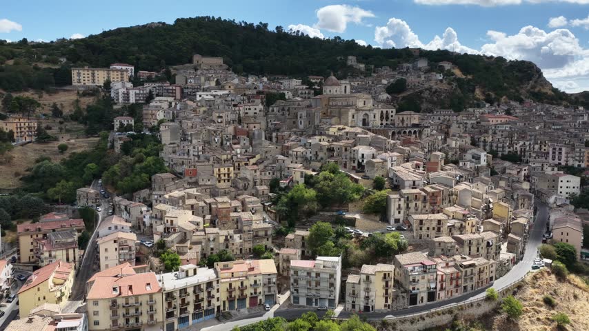 Aerial drone view of Petralia Sottana in Sicily, Italy, showing historic sicilian town buildings, churches, rooftops and traditional architecture surrounded by the Madonie mountain landscape. Sicilian hill town.