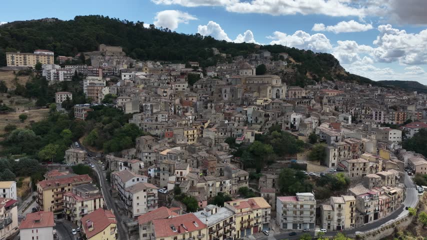 Aerial drone view of Petralia Sottana in Sicily, Italy, showing historic sicilian town buildings, churches, rooftops and traditional architecture surrounded by the Madonie mountain landscape. Sicilian hill town.