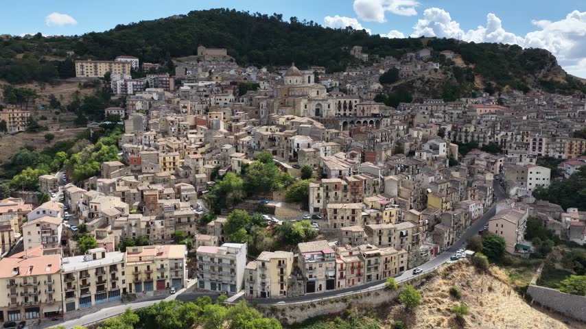 Aerial drone view of Petralia Sottana in Sicily, Italy, showing historic sicilian town buildings, churches, rooftops and traditional architecture surrounded by the Madonie mountain landscape. Sicilian hill town.