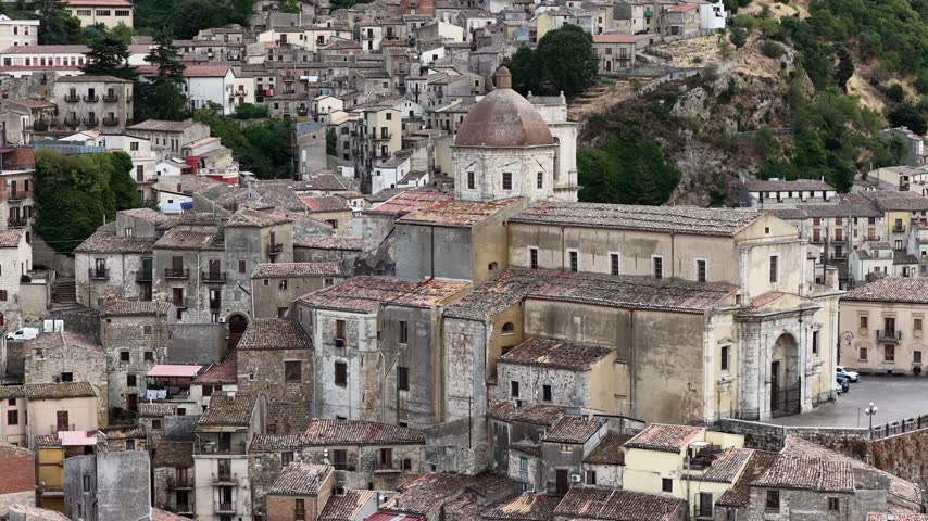 Aerial drone view of Petralia Sottana in Sicily, Italy, showing historic sicilian town buildings, churches, rooftops and traditional architecture surrounded by the Madonie mountain landscape. Sicilian hill town.