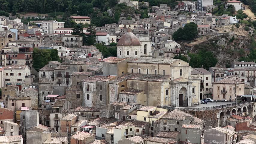 Aerial drone view of Petralia Sottana in Sicily, Italy, showing historic sicilian town buildings, churches, rooftops and traditional architecture surrounded by the Madonie mountain landscape. Sicilian hill town.