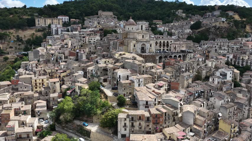 Aerial drone view of Petralia Sottana in Sicily, Italy, showing historic sicilian town buildings, churches, rooftops and traditional architecture surrounded by the Madonie mountain landscape. Sicilian hill town.
