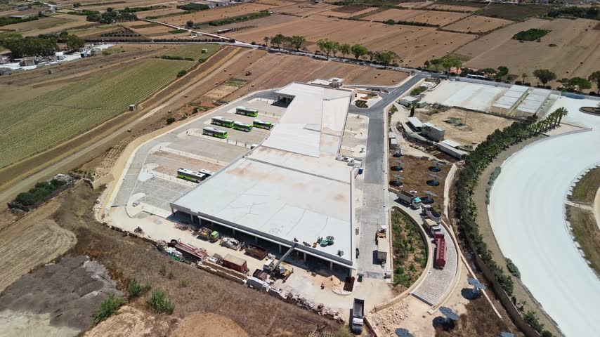 Xewkija, Gozo, Malta bus terminal and Park and Ride facility with buses, parking areas and transport infrastructure on a Mediterranean island, viewed by drone.