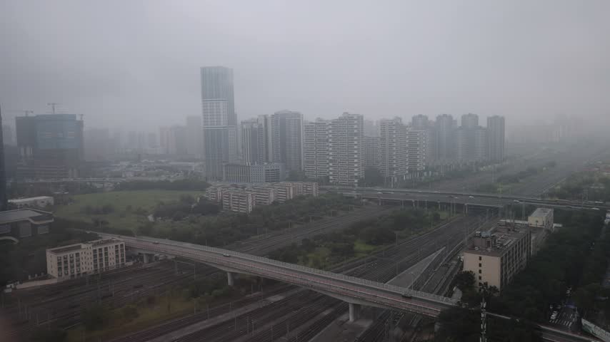 Aerial view of Chengdu East Station with surrounding urban skyline, railway tracks, and highway infrastructure in Chengdu, Sichuan, China.