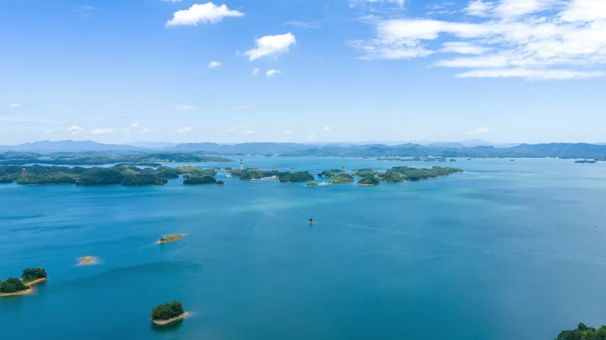 Aerial view of vast lake water and green islands under blue sky