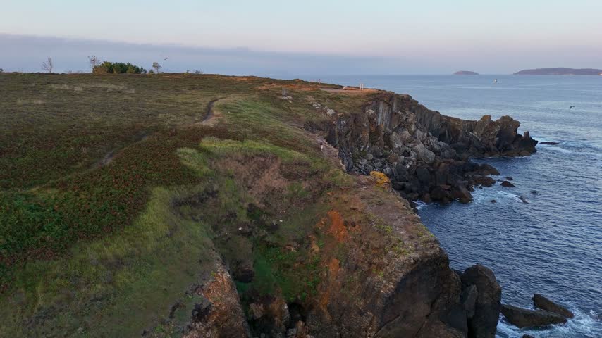 Person Exploring Rugged Seaside Cliffs at Dawn