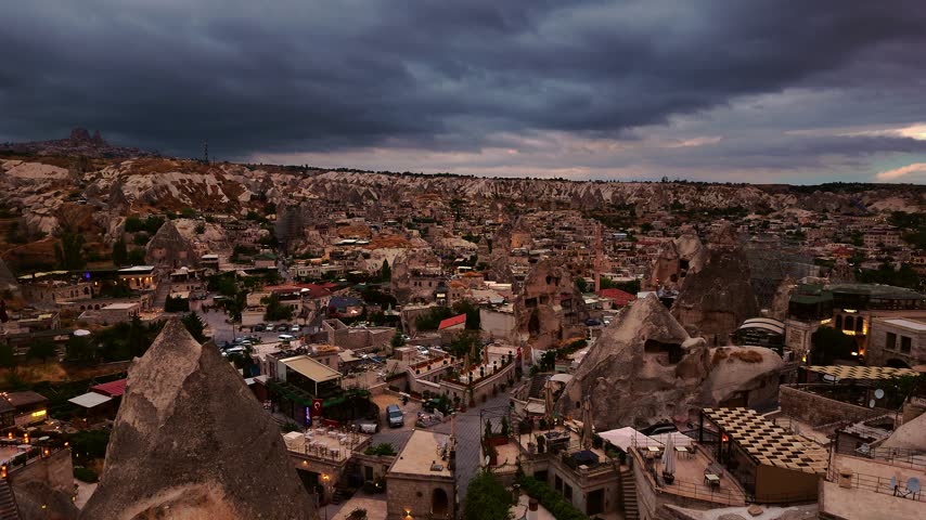 Wide view over Goreme village and unique rock formations under dramatic sunrise clouds