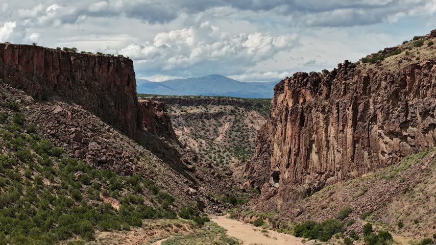 Aerial view of the rugged rock formations and desert landscape of Diablo Canyon under dramatic clouds in Santa Fe, New Mexico, United States.