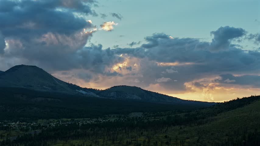 Aerial view of San Francisco Peaks during sunset with dramatic clouds over the forested landscape near Flagstaff, Arizona, United States.