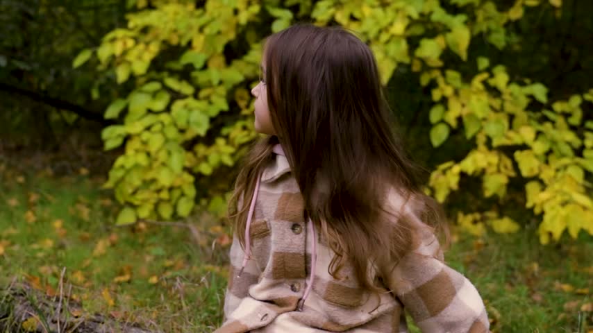 Tracking shot of girl enjoying nature while exploring forest path in autumn