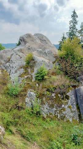 Massive rock formations and ancient stone ruins surrounded by dense evergreen forest in mountains