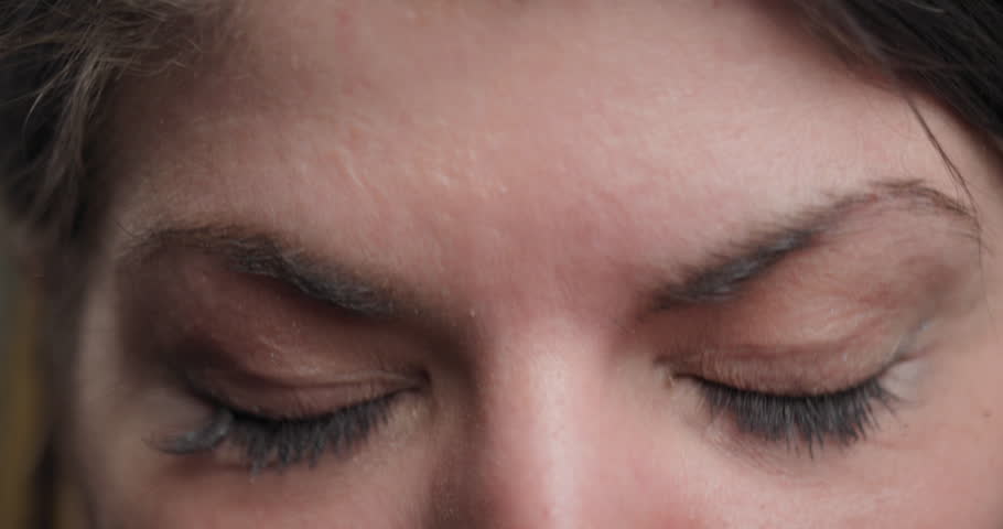 Intimate portrait of a young woman deep in thought, hand partially covering her face, highlighting her eyes and subtle expression.