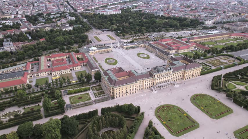 4K drone aerial view of a historic palace and surrounding cityscape in Vienna, Austria. Ornate architecture, landscaped grounds and dense urban buildings create a distinctive European scene.