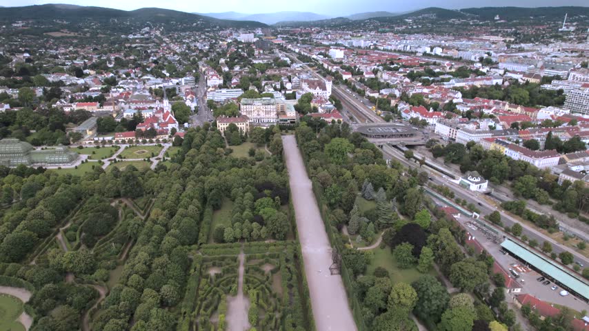 4K drone aerial view of a historic palace and surrounding cityscape in Vienna, Austria. Ornate architecture, landscaped grounds and dense urban buildings create a distinctive European scene.