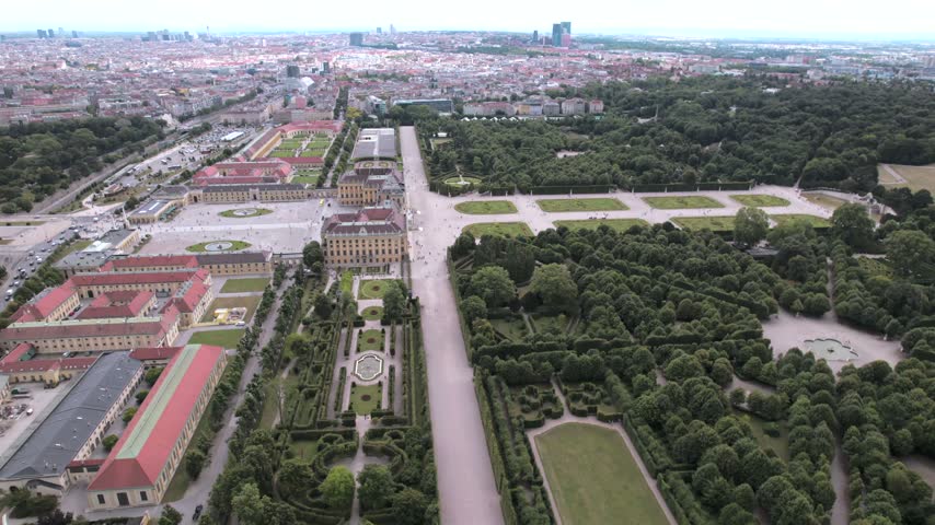 4K drone aerial view of a historic palace and surrounding cityscape in Vienna, Austria. Ornate architecture, landscaped grounds and dense urban buildings create a distinctive European scene.