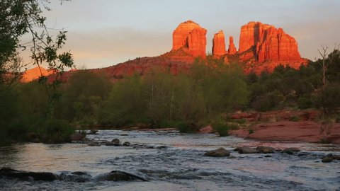 Cathedral Rock glowing red-orange reflecting the last rays of the sun, with Oak Creek in the foreground; Sedona, Arizona.