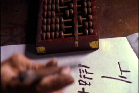 SONG DYNASTY VILLAGE, CHINA - NOVEMBER 09, 1999: CU of hands counting beads on an abacus, then transcribing the numbers on white paper.
