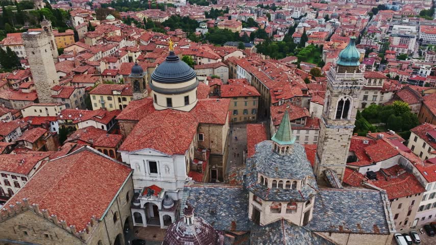 Aerial drone view of Basilica di Santa Maria Maggiore and Bergamo Cathedral in Bergamo, Italy, showcasing historic churches, domes, bell towers, ornate architecture, and the medieval Città Alta.