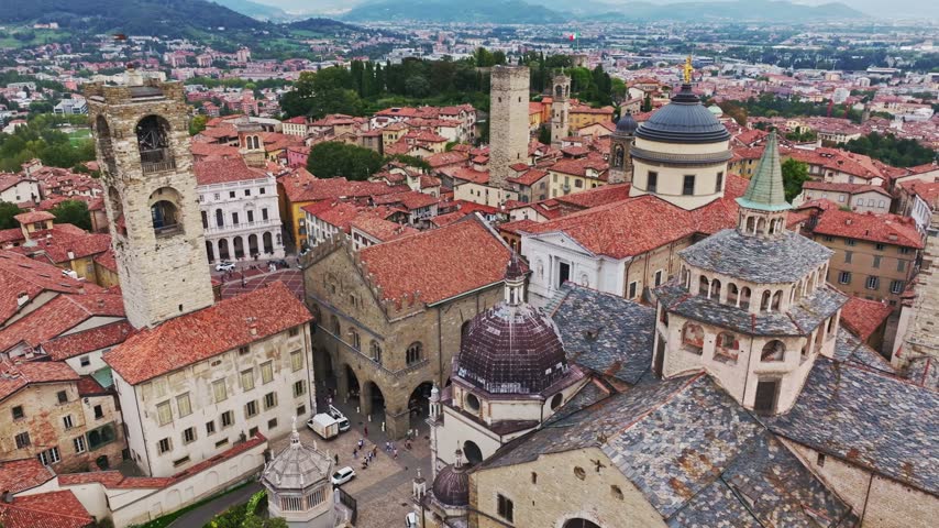 Aerial drone view of Basilica di Santa Maria Maggiore and Bergamo Cathedral in Bergamo, Italy, showcasing historic churches, domes, bell towers, ornate architecture, and the medieval Città Alta.