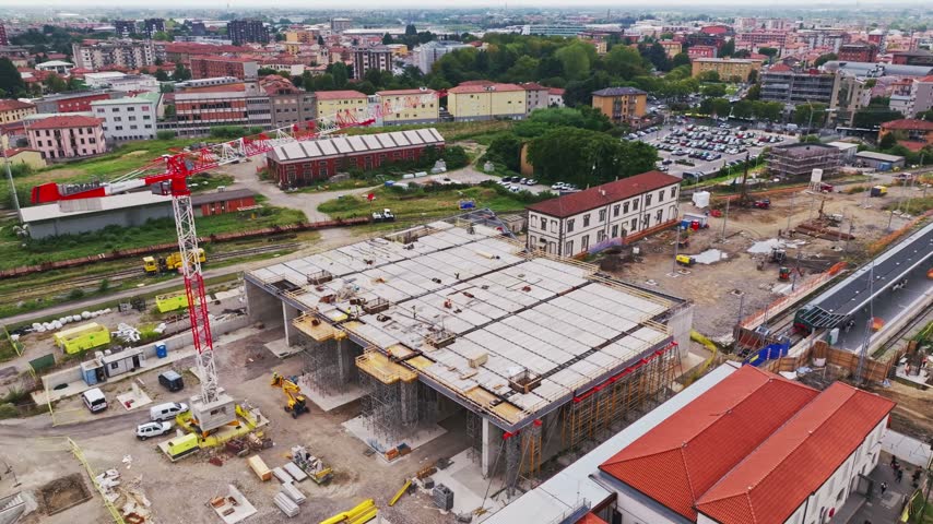 Aerial drone view of construction works near Bergamo Railway Station, Italy, showing concrete pillars, heavy machinery, cranes, scaffolding, and developing transport infrastructure.