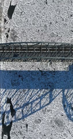 Traffic moving across a bridge over a river covered in ice floes. Aerial view on winter in Poland.