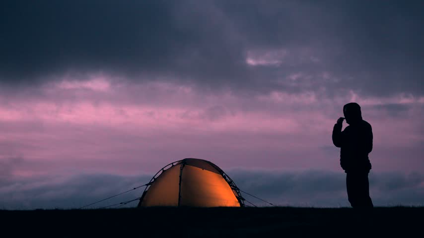 Silhouette of a man brushing his teeth while camping