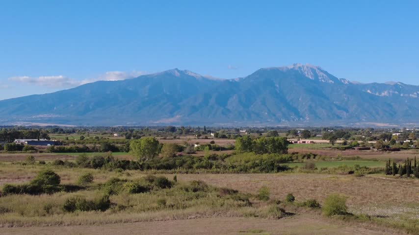 Aerial view of the majestic Mount Olympus rising above the fields and coastal landscape of Paralia Katerinis, Pieria, Greece.